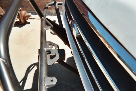 1990 Ford Bronco - Close detail of a black tubular bumper, mounting bracket and chrome trim against a vehicle's body panel.
