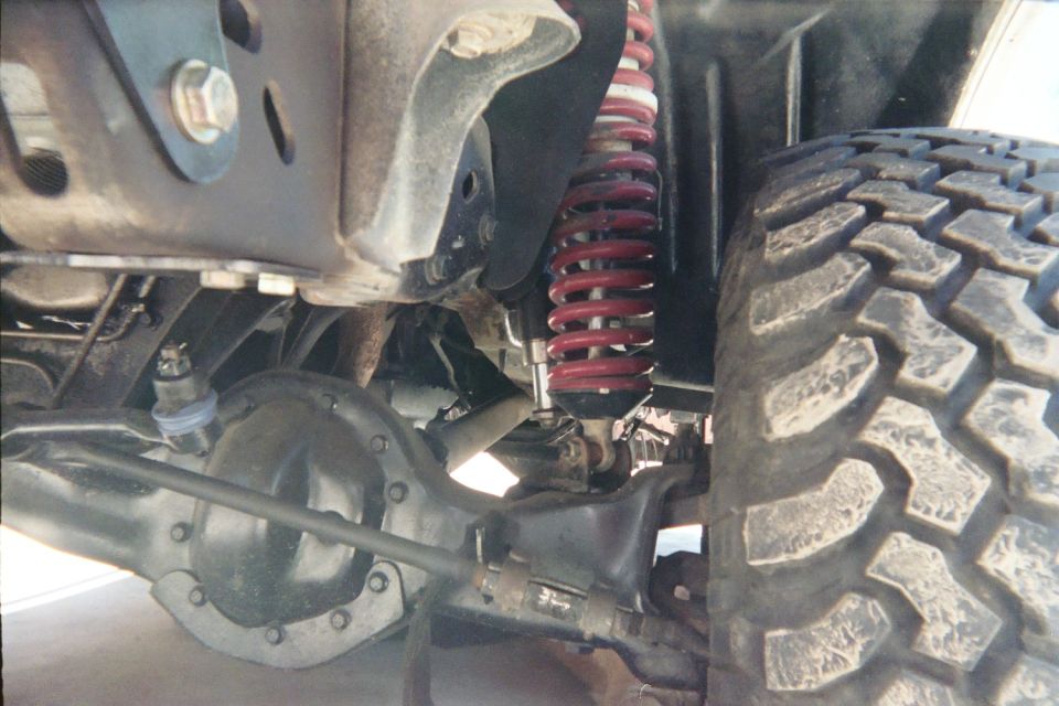 Front suspension detail with red coil spring, axle and mud tire