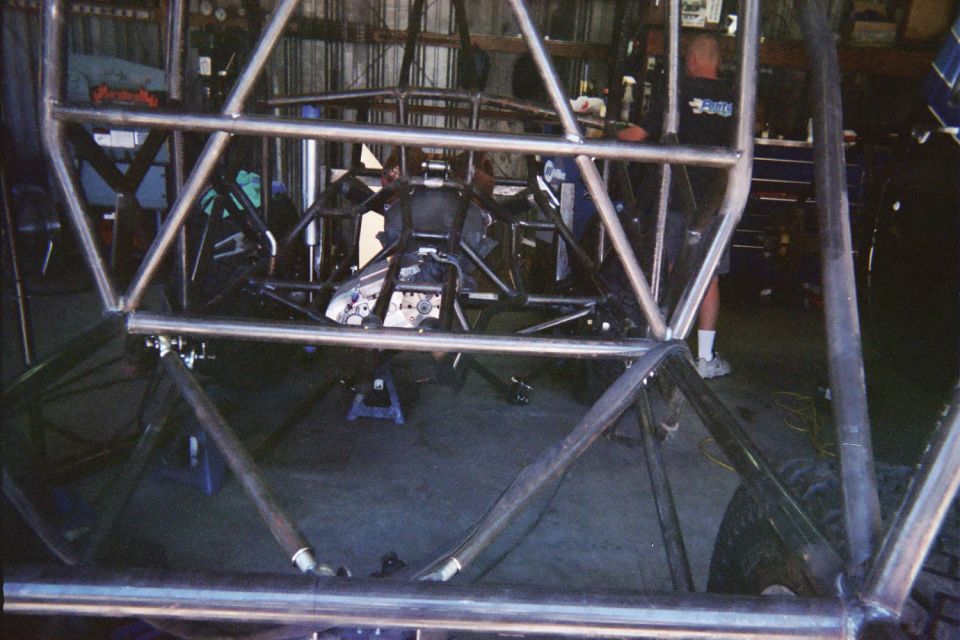 Bare welded tube-frame chassis of an off-road vehicle under construction in a garage