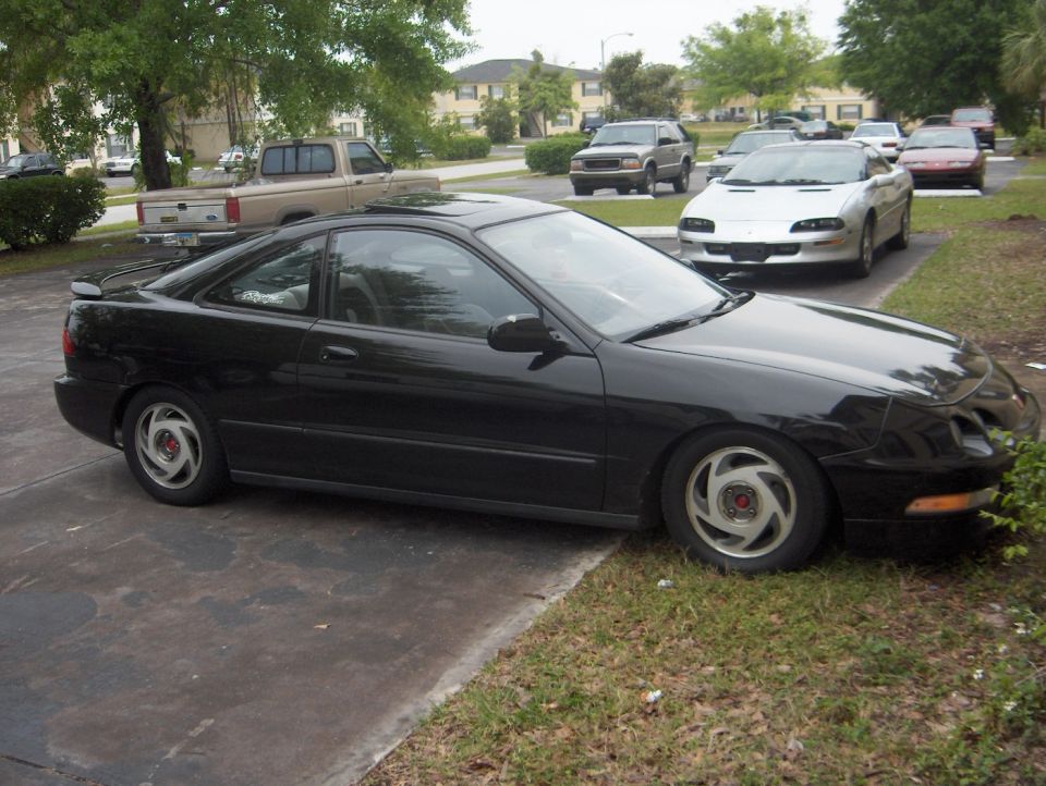 Black 1994 Acura Integra coupe with a rear spoiler, parked on a driveway