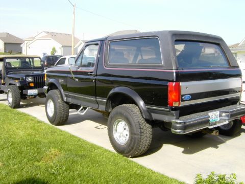 1991 Ford Bronco - A black 1991 Ford Bronco is parked on a driveway next to a Jeep Wrangler on a sunny day.