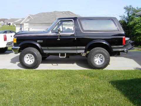 1991 Ford Bronco - Side view of a black Ford Bronco, likely a 1992 model, with custom wheels and lifted suspension.