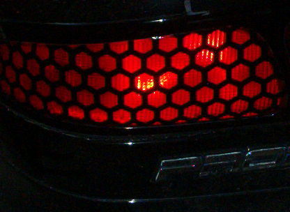 1995 Ford Probe - A close-up view of a car's red taillight with a distinctive honeycomb pattern. Text is visible on the lower right.