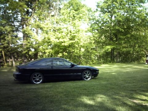 1995 Ford Probe - Side view of a black 1995 Ford Probe parked on a lawn with trees.