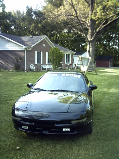 1995 Ford Probe - A black 1995 Ford Probe is parked on a grassy lawn in front of a suburban house.
