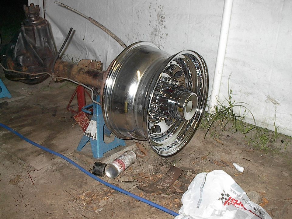 Rear axle assembly with a shiny chrome dually wheel on jack stands