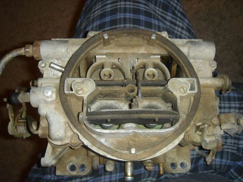 1986 Ford Mustang - A close-up view of a carburetor, a critical engine component, is shown against a plaid background.