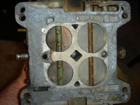 1986 Ford Mustang - This image shows a close-up view of a four-barrel carburetor, highlighting its internal components like the throttle plates.