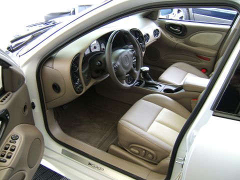 1998 Ford Taurus - Driver's-side interior of a white Pontiac Bonneville GXP sedan viewed through the open front door, showing two-tone tan leather seats, a le…