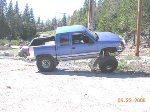 1994 Ford Bronco - A lifted blue pickup truck navigates rough terrain, with a date stamp of May 23, 2005 visible.