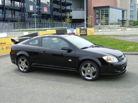 1998 Ford Taurus - A black coupe with a spoiler is seen from a three-quarter front angle in front of a stadium.