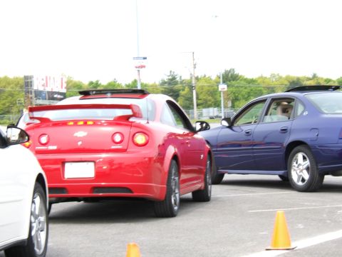 1998 Ford Taurus - Two cars, a red coupe and a blue sedan, are parked next to each other on pavement with cones.