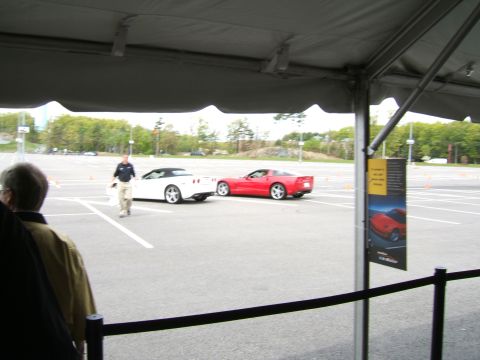 1998 Ford Taurus - Two sports cars, a red coupe and a white convertible, are visible on a paved lot marked with orange cones.