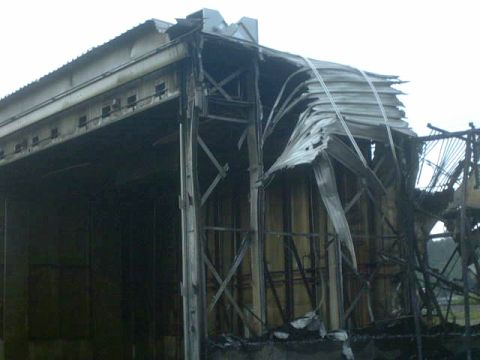 1995 Ford Bronco - A building shows extensive damage from a fire, with its roof and walls partially destroyed.