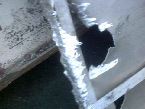 1995 Ford Bronco - A close-up view reveals a large, jagged hole in a metal panel, with torn edges suggesting significant damage.