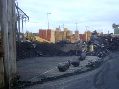 1995 Ford Bronco - A view of an industrial area with lumber stacks and scattered debris under an overcast sky.