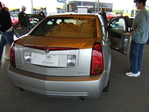 1998 Ford Taurus - Silver Cadillac CTS parked at an outdoor event with people around.