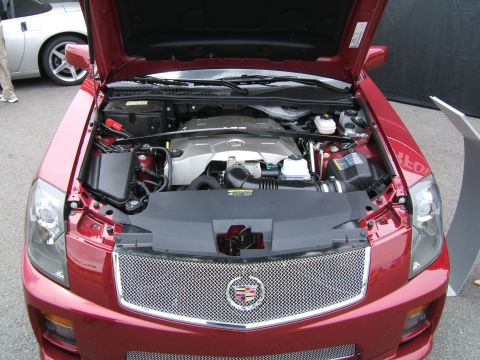 1998 Ford Taurus - The engine bay of a red Cadillac CTS-V is displayed, with another vehicle visible behind it.
