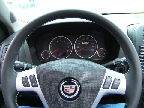 1998 Ford Taurus - The interior of a car is shown, a steering wheel with a Cadillac emblem and dashboard gauges indicating V8 power.