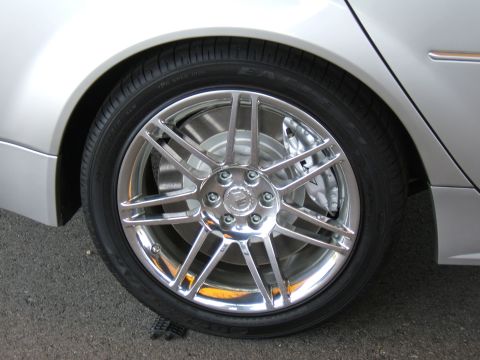1998 Ford Taurus - Close-up of a silver car's wheel and tire, showing custom chrome rims and brake system.