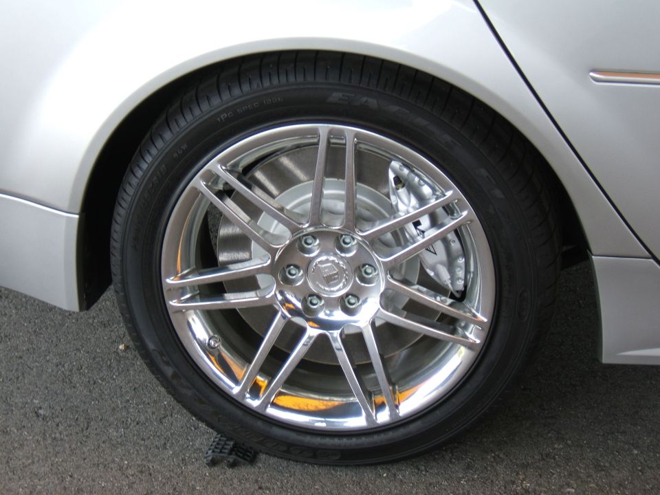 Silver car's chrome wheel with multi-spoke design and visible brake caliper