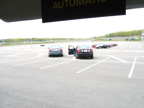 1998 Ford Taurus - Cars are parked in an open lot with cones, suggesting a driving event or test.