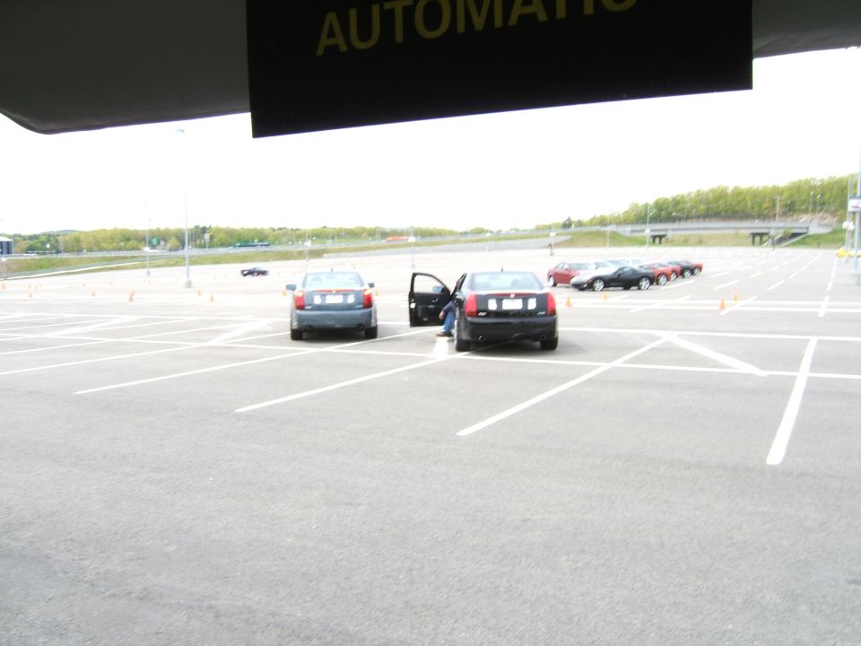 Two sedans parked in a lot, one with door open, others in background