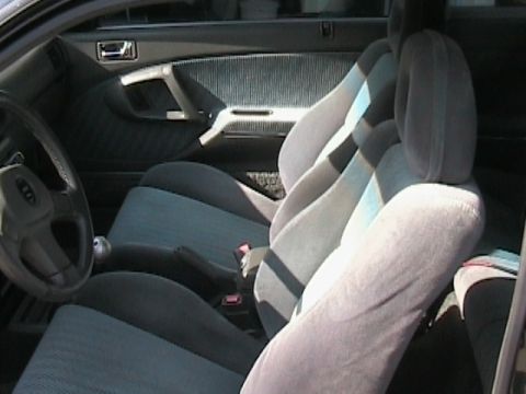 1989 Mazda MX-6 - Interior view showing front seats, door panel, and steering wheel of a car.