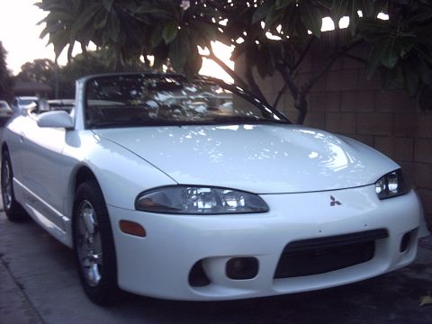 1998 Mitsubishi Eclipse - A white convertible sports car is parked outdoors, showing its front 3/4 view under dappled sunlight.