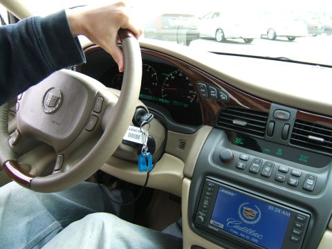 1998 Ford Taurus - Interior view of a Cadillac, showing the steering wheel, dashboard, and climate controls. Other vehicles are visible outside.