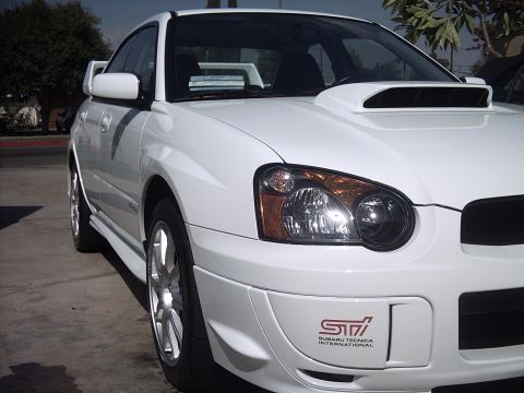 2005 Subaru Impreza - This white Subaru Impreza WRX STI is shown from the front quarter angle, an STI badge.