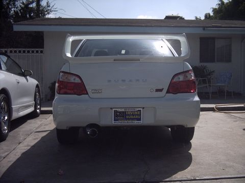 2005 Subaru Impreza - Rear view of a white 2005 Subaru Impreza WRX STI sedan with a large spoiler. Another car is visible to the left.