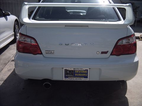 2005 Subaru Impreza - The rear of a white Subaru WRX STI is shown, its distinctive spoiler and WRX STI badging.