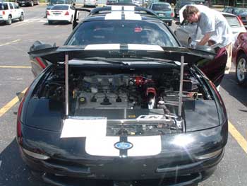 1997 Ford Probe - A man works on the engine of a black 1997 Ford Probe with white racing stripes.
