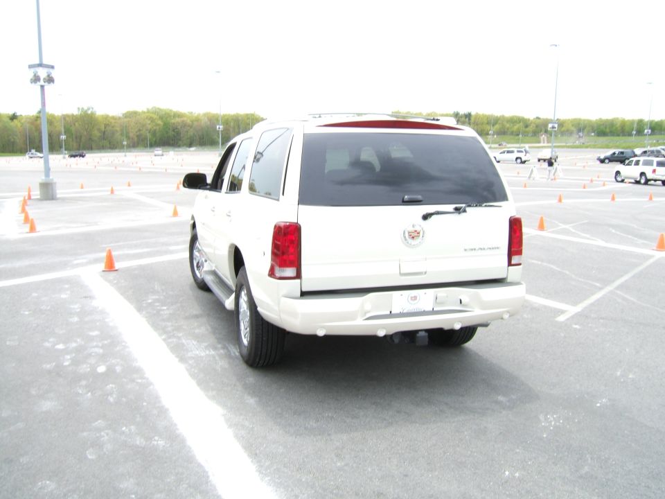 Rear view of white Cadillac Escalade parked in a lot with orange cones
