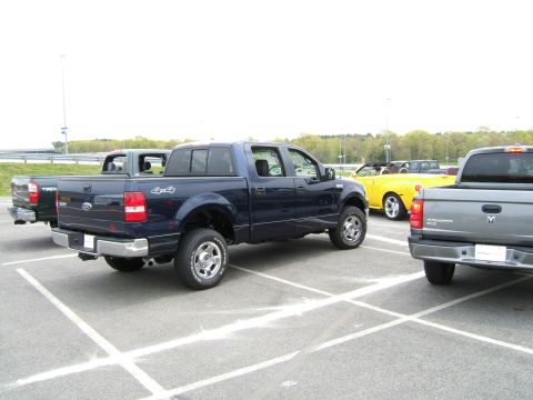 1998 Ford Taurus - A dark blue Ford F-150 pickup truck is parked in a lot alongside other vehicles.