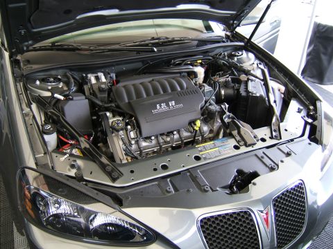 1998 Ford Taurus - The engine bay of a gray car is shown with the hood open, revealing the V8 engine and front grille.