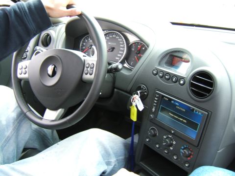 1998 Ford Taurus - The interior of a car is shown, the steering wheel, instrument cluster, and a central infotainment display.
