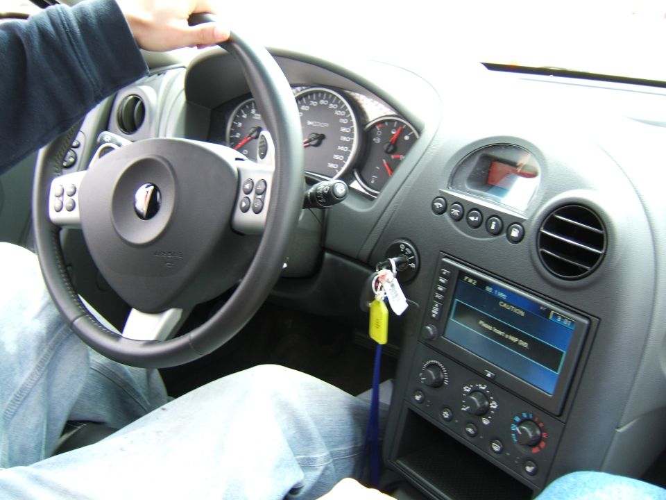 Interior view of car dashboard with steering wheel, gauges, and infotainment screen