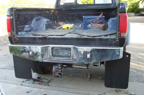 1994 Ford F-150 - The rear of a black 1994 Ford F-150 pickup truck is shown, a chrome bumper, mud flaps, and tools scattered around the tailgate area.