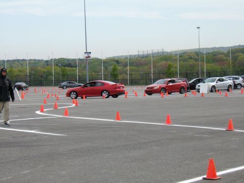 1998 Ford Taurus - Multiple cars navigate an autocross course marked with orange cones on a paved lot.