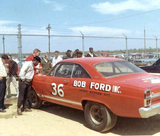 Red number 36 Ford race car with Bob Ford Inc lettering, men standing beside it by a fence