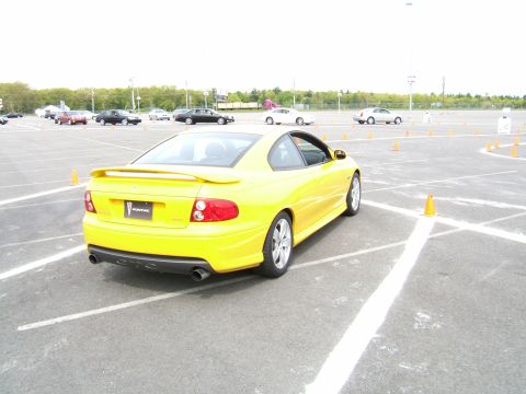 1998 Ford Taurus - Yellow Pontiac GTO at a car event with cones and other vehicles visible.