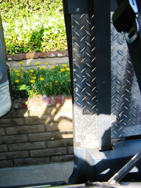 1985 Ford Bronco - Diamond plate interior paneling and a seatbelt are visible from inside the vehicle.