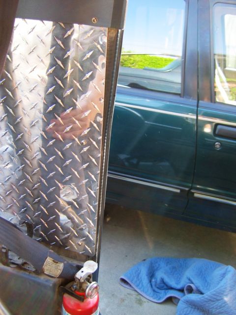 1985 Ford Bronco - A diamond plate panel is visible inside a vehicle, next to the side of a dark green SUV.
