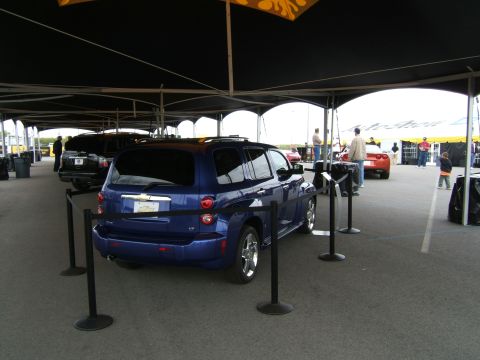 1998 Ford Taurus - A blue SUV is displayed under a tent at an outdoor event with other cars and attendees.