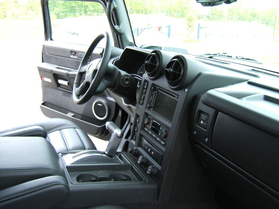 Black SUV interior with steering wheel, center stack controls, vents, and leather seats