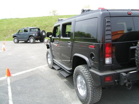 1998 Ford Taurus - Two Hummer H2 SUVs are parked on asphalt, with one in the foreground and another in the background.
