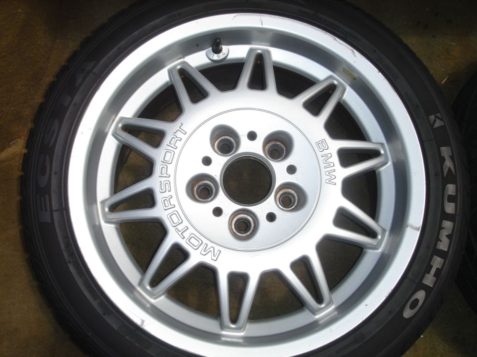 BMW Motorsport silver wheel mounted on Kumho tire lying on cardboard