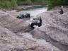 1977 Chevrolet Blazer - Off-road vehicles navigate a challenging rocky stream bed in a natural setting.